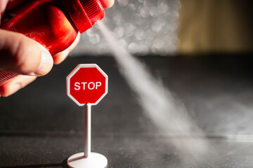 Using a red spray can with deodorant against a stop sign, environmental issue concept, soft focus