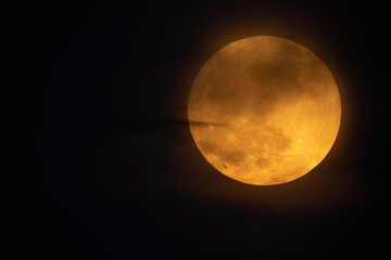 Moon looks orange and you can see the craters. Photography taken with a telescope.