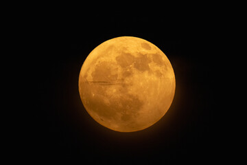 Moon looks orange and you can see the craters. Photography taken with a telescope.