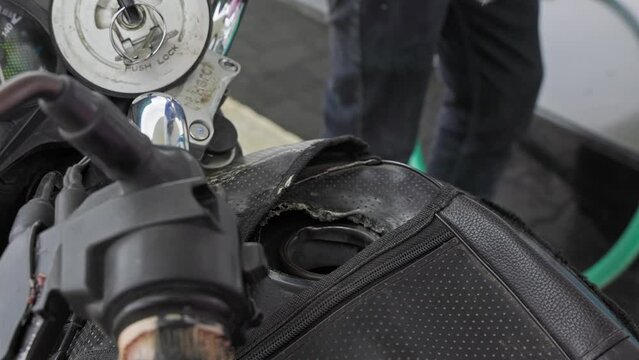 A close-up of refueling a motorcycle with gasoline at a petrol station