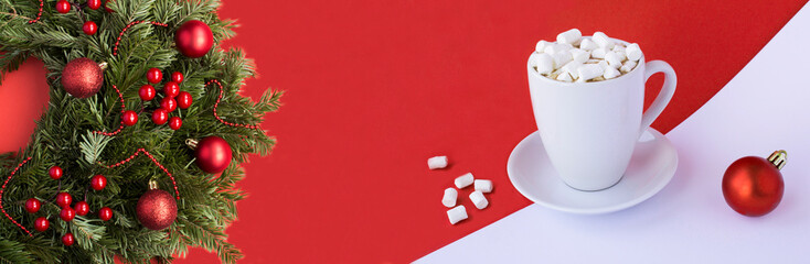 Christmas ring or wreath with red bead and hot chocolate with marshmallows in the cup on the red background. Copy space.
