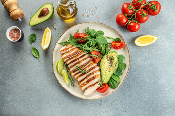 Fresh green salad with grilled chicken fillet, tomatoes, avocado, lemon on light background. Diet Concept. Top view copy space