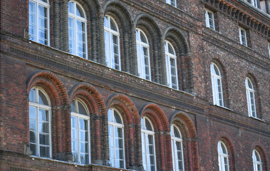 Old wooden windows on the facade of an old brick building with a water pipe
