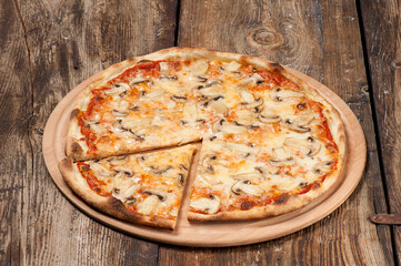 Studio shot of a hand made mushroom pizza with a cut slice on beautiful weathered wooden table
