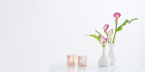 pink calla lily in vase  and burning candles on white background - obrazy, fototapety, plakaty