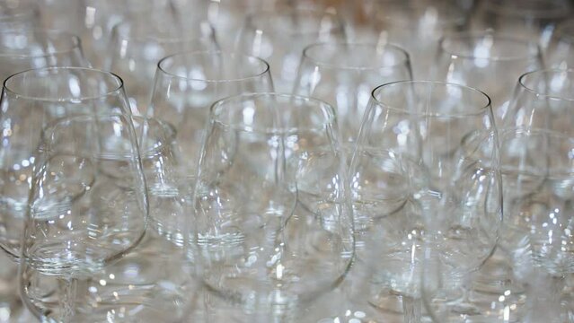 empty glasses neatly lined up on the sleek bar countertop. The crystal-clear vessels await the skilled hands of bartenders, ready to be filled with crafted libations . High quality 4k footage