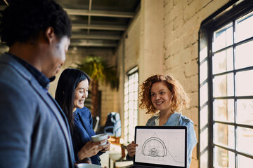 Young colleagues going over designs on a laptop in a startup company office