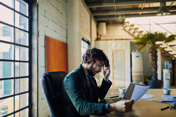 Young man going over paperwork while working for a startup company in an office