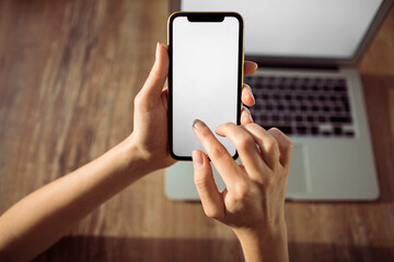Young Caucasian woman using a smartphone and laptop with blank screens