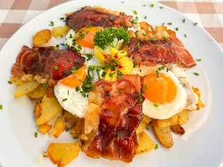 Delicious traditional Tyrolean mountain dish with cut grilled potatoes, speck and eggs