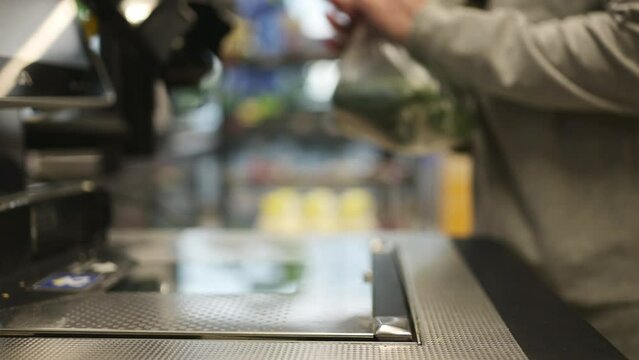 girl Waights a plastic bag with a cucumbers on a self-service checkout