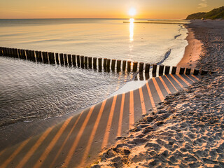 Sun rays passing through breakwater at sunrise, Baltic sea.