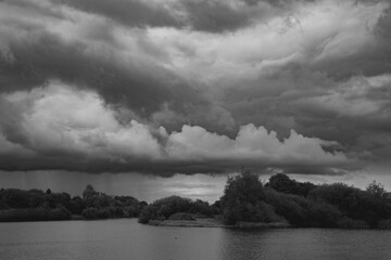 Dark rain clouds arrive over the lake in the UK.  Black and white image