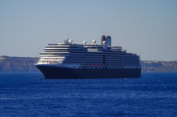 Luxury cruiseship cruise ship liner Eurodam anchoring at sea on sunny summer day during Mediterranean Greek Island cruise with shore and rocky island in background
