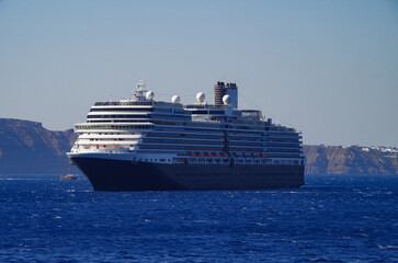 Luxury cruiseship cruise ship liner Eurodam anchoring at sea on sunny summer day during Mediterranean Greek Island cruise with shore and rocky island in background
