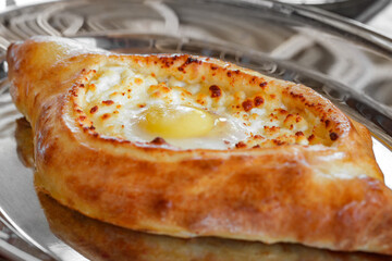 Adjarian khachapuri with raw egg, side view, selective focus