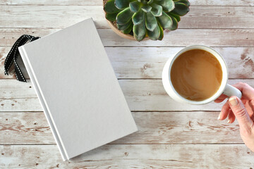 Blank book cover for mock up with coffee, plant and female hand.
