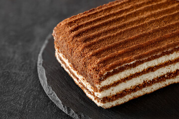 Layered chocolate cake on slate stone plate round, dark background, selective focus, side view