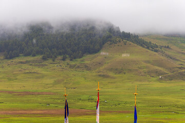 View of green valley with clouds over mountains in the background located in Bhutan.