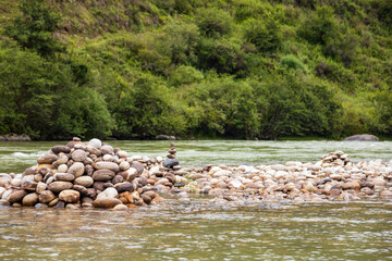 View of a river flowing in a valley surrounded by greenery with clouds over mountains in Bhutan.