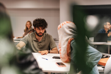 Fototapeta premium Young, multicultural teammates brainstorming together at table in the office.