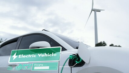 Electric car recharging energy from EV charging station display futuristic smart battery status hologram by EV charger plug cable in wind turbine farm. Alternative clean energy sustainability. Peruse
