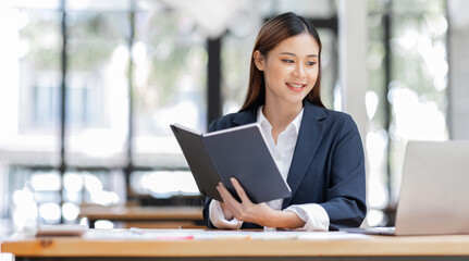 Obraz premium Asian Business woman using calculator and laptop for doing math finance on an office desk, tax, report, accounting, statistics, and analytical research concept 