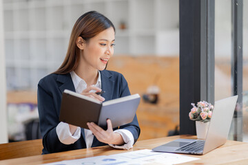 Asian Business woman using calculator and laptop for doing math finance on an office desk, tax, report, accounting, statistics, and analytical research concept
