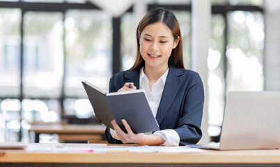 Asian Business woman using calculator and laptop for doing math finance on an office desk, tax, report, accounting, statistics, and analytical research concept
