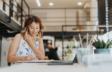 Happy, smiley, successful female broker discussing with client during phone call at work.