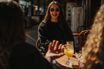 Front view shot of lovely brunette girl wearing sunglasses smiling while having fun conversation with her friends