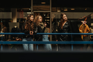 Lovely brunette girl pointing at boutique in the shopping mall. She wants to go there and check if there is something new