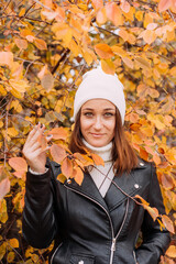 Portrait of a woman in the park in autumn. Girl in a white hat.