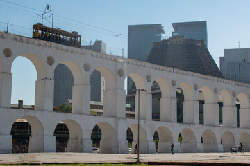 Fototapeta premium Rio de Janeiro, Brazil: the Carioca Aqueduct, known as Arcos da Lapa, example of colonial architecture, with the famous bonde cable car, electric tram on its way between Centro and Santa Teresa 