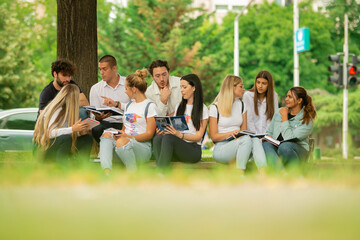 University or high school students sitting outside on the sidewalk, pavement