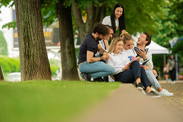 Fototapeta premium University or high school students sitting outside on the sidewalk, pavement