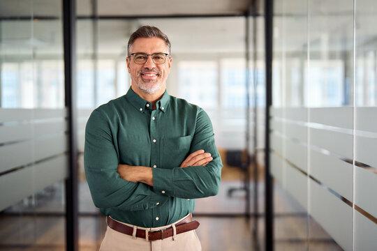 Smiling older bank manager or investor, happy middle aged business man boss leader, confident mid adult professional businessman executive standing in office hallway, mature entrepreneur portrait.