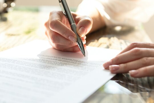 Businesswoman's Hand Signing Contract With Pen