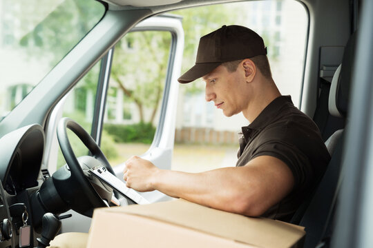 Delivery Man Checking List In Van