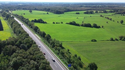 Aerial view on the A7 motorway in northern Germany between fields and meadows.