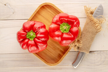 Two sweet red peppers with bamboo tray, knife  on wooden table, macro, top view.