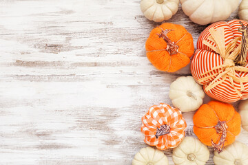 Autumn farmhouse pumpkin side border over a white wood background. Rustic orange and white cloth pumpkins. Above view with copy space.