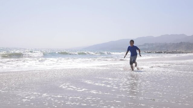12 year old boy running on the beach in Santa Monica. Slow Motion.