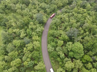 curvy highway road in the forest red bus india
