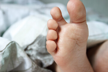 Feet under a light blanket on the bed. Concept of health