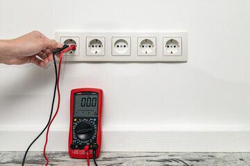 Man checking the voltage of electricity at a home outlet