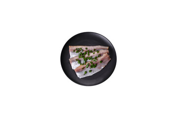 Delicious fresh herring fillet with salt, spices and herbs on a black plate