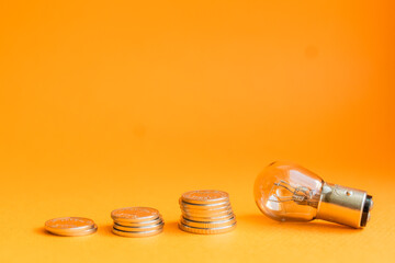 A lamp and money on a orange
 background with copy space. Price for electricity concept. Expensive electricity cost.