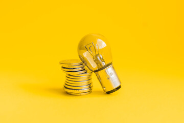 A lamp and money on a yellow background with copy space. Price for electricity concept. Expensive electricity cost.