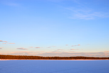 Winter landscape at sunset, with a frozen lake covered with snow in winter on a cold day, in Sweden Lappland, Europe